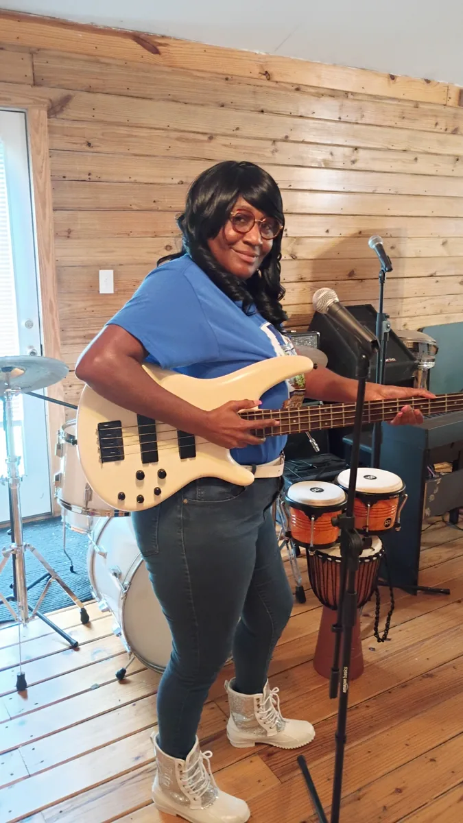 Musician playing an electric bass indoors at Young Family Farm